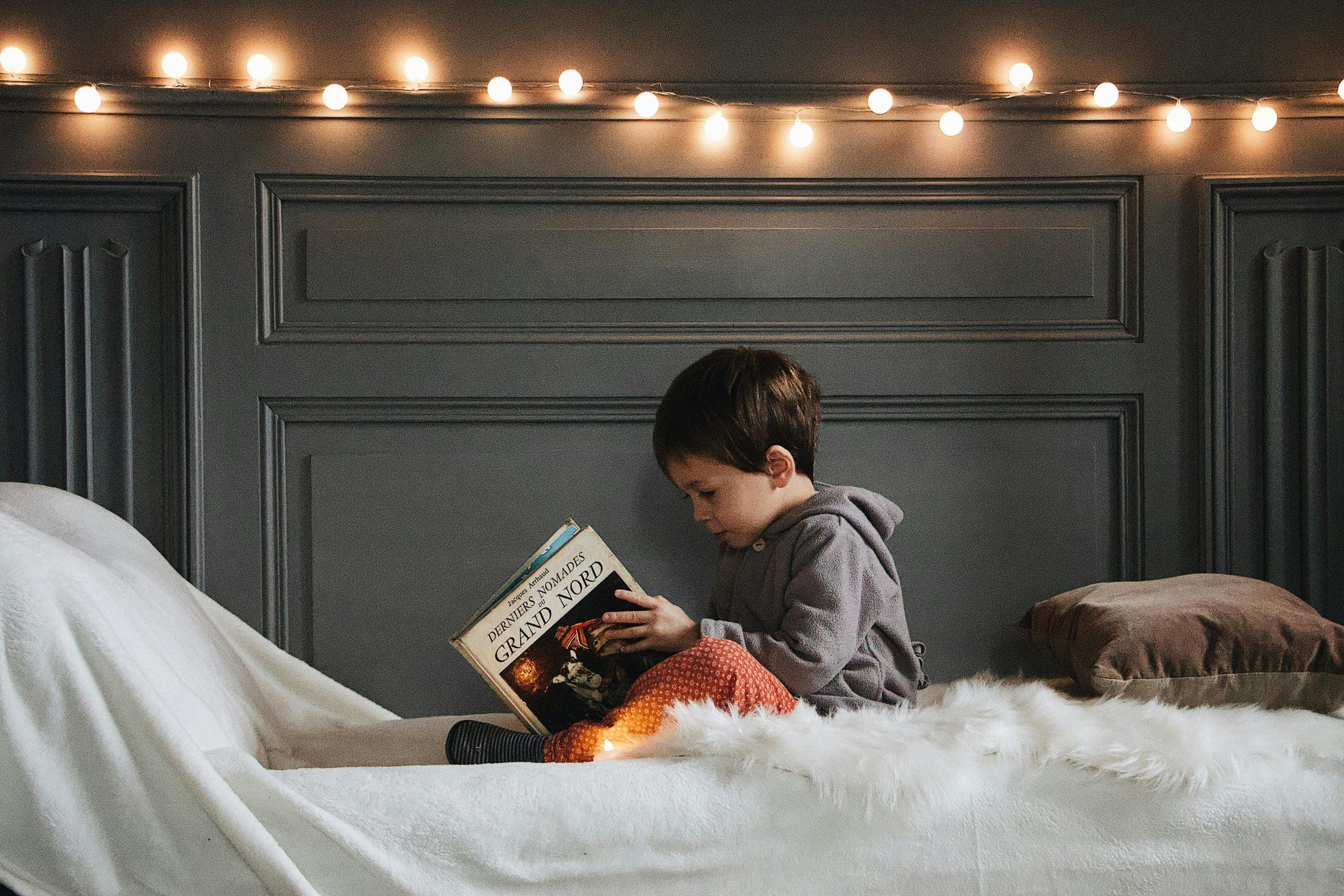 Child holding a childrens book cover idea book on a white surface