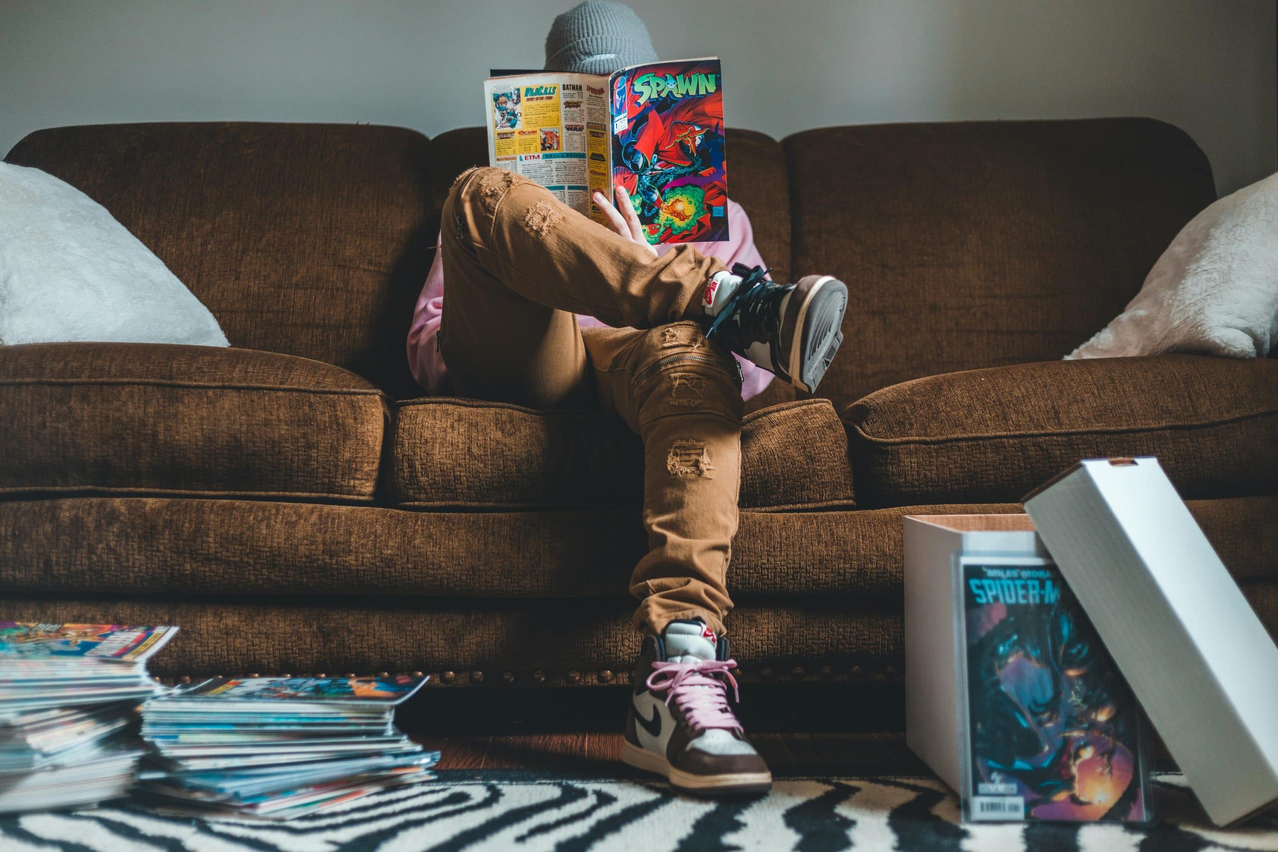 Young man sitting on sofa and reading comics magazine