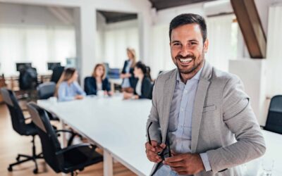 Professional business man sitting on a conference room table with three other employees behind him