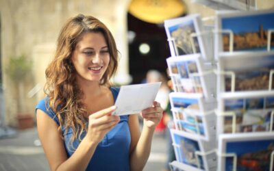 Woman holding a postcard in front of a stand filled with postcards