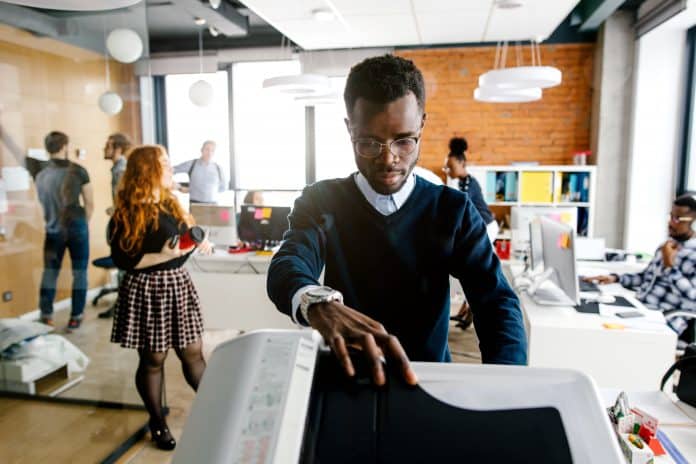 Man at a small office printer in a start up company environment