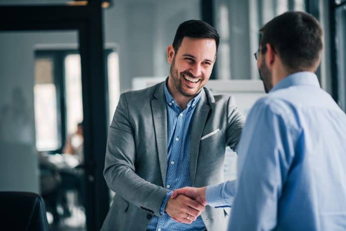 Portrait of cheerful young manager handshake with new client