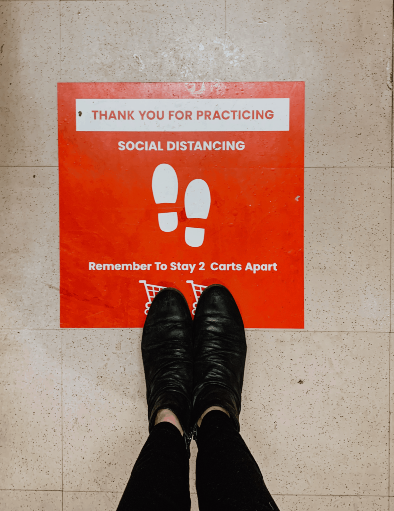 Woman standing on a floor decal sticker to encourage social distancing