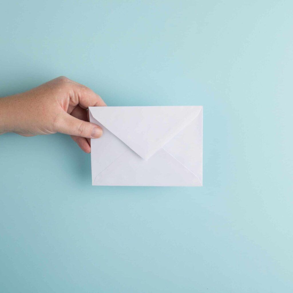 hand holding an envelope over blue background