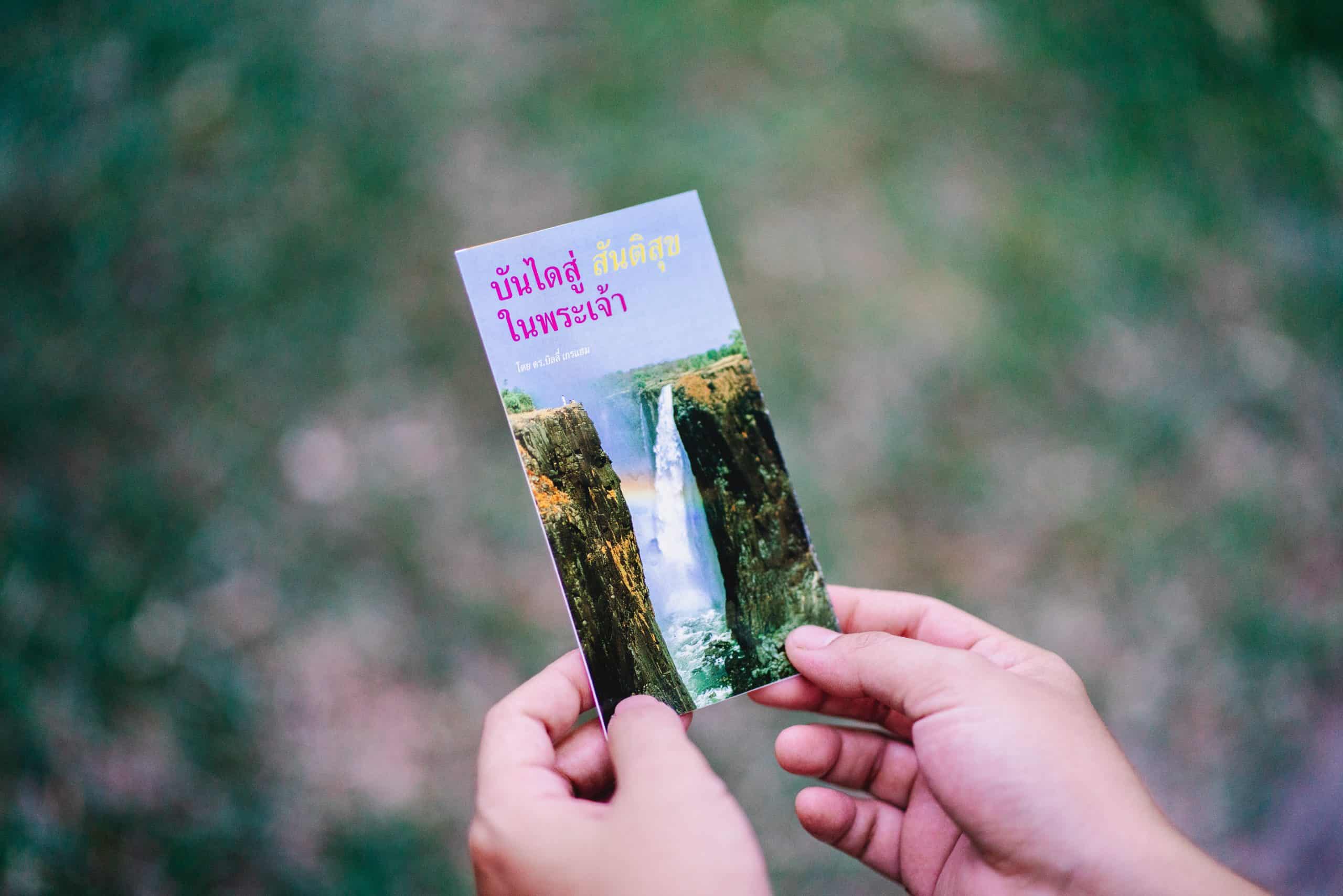 Hands holding a travel brochure with waterdalls