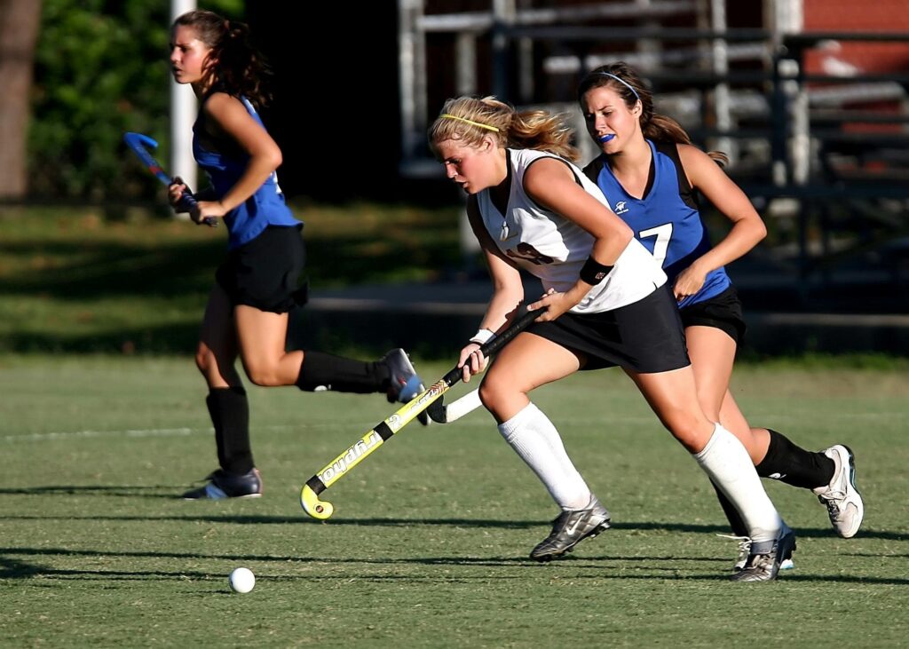 Young women play lacrosse. 