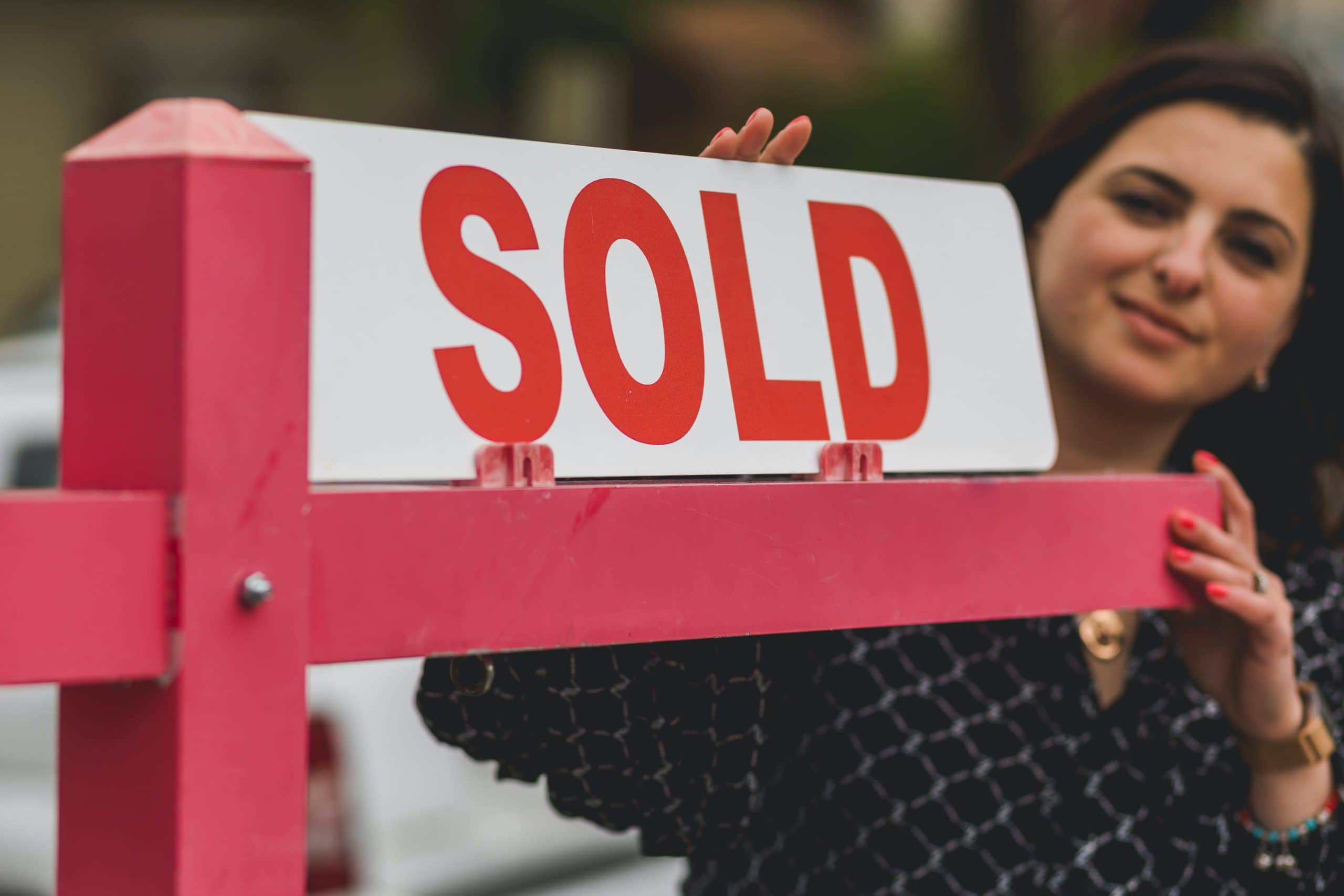 Red sold sign with a person looking at it