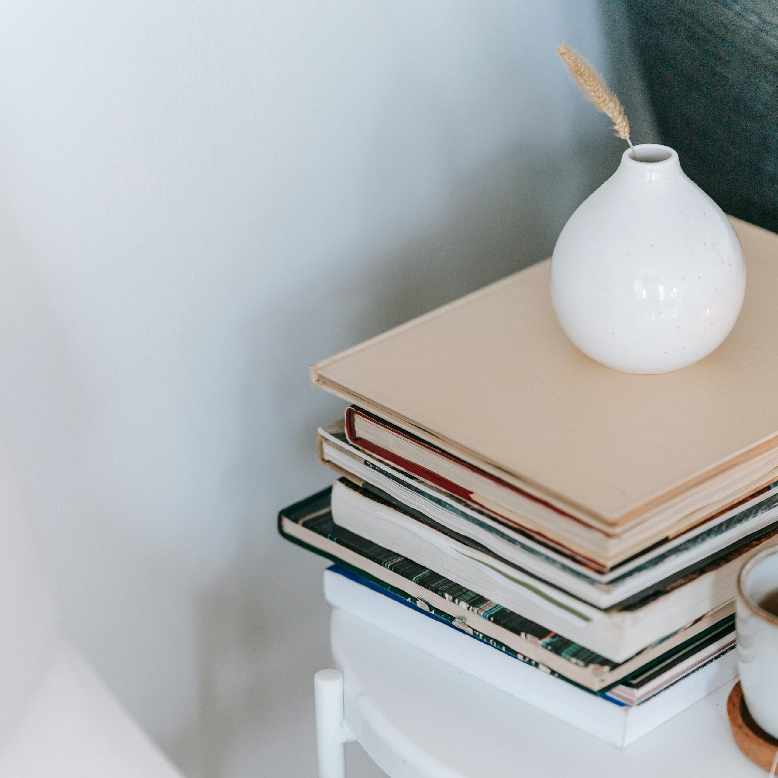 A stack of hardcover books on a white table