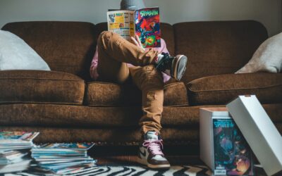 Young man sitting on sofa and reading comics magazine